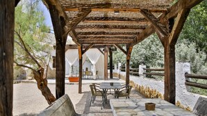 An outdoor patio with a wooden pergola, stone tables, and chairs.