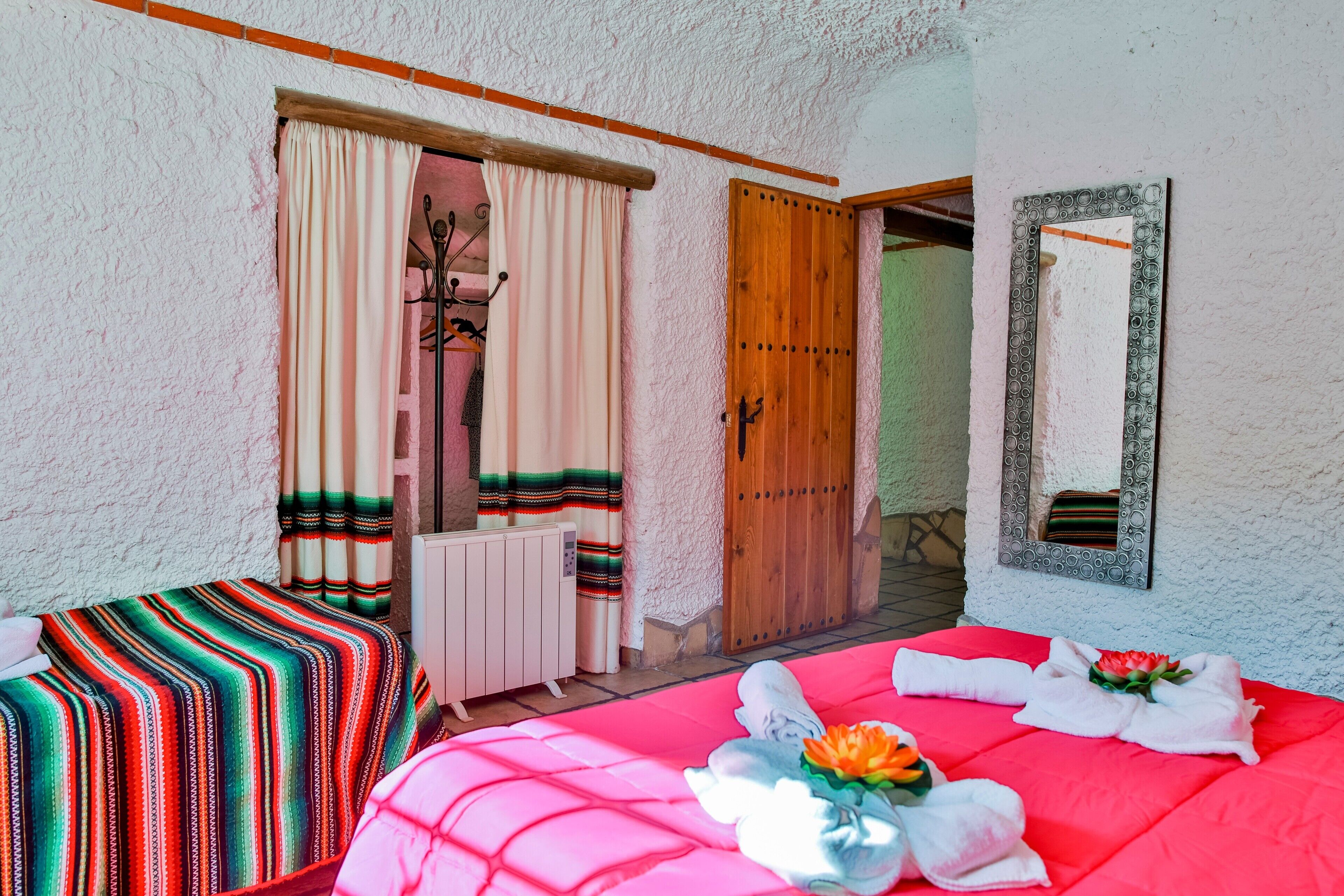 Una habitación con una cama, un radiador, una puerta de madera y un espejo en la pared.