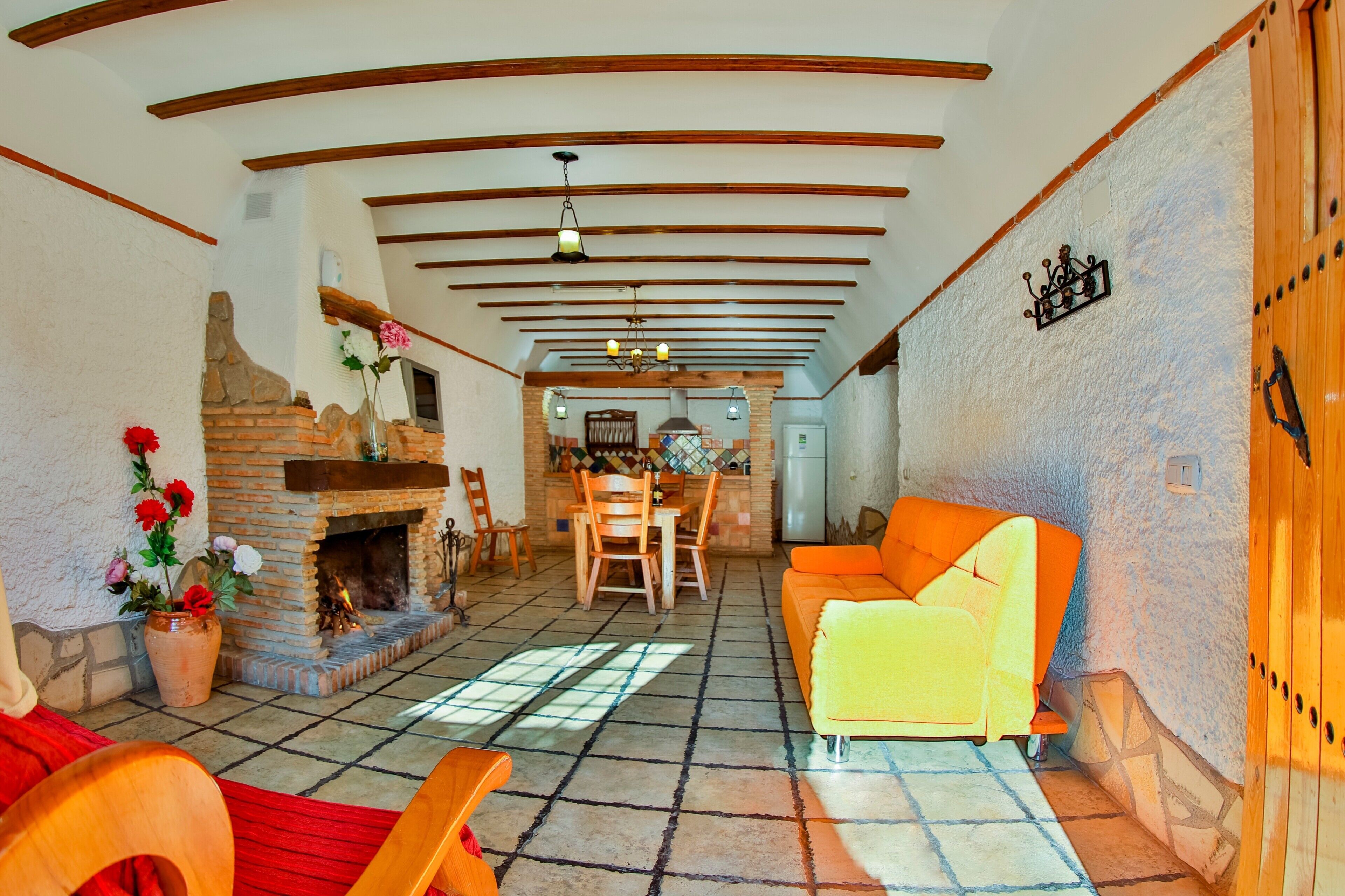 A cozy living room with a fireplace, wooden furniture, and a stone wall.