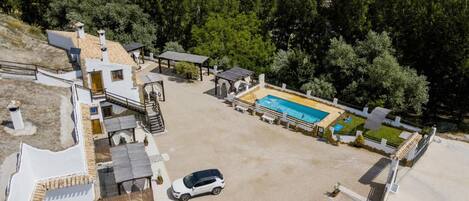 A residential property with a swimming pool, solar panels, and a car parked in the driveway.