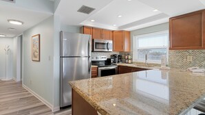 A modern kitchen with granite countertops, stainless steel appliances, and wooden cabinets. - Gulf Gate Resort (St. Pete Beach)