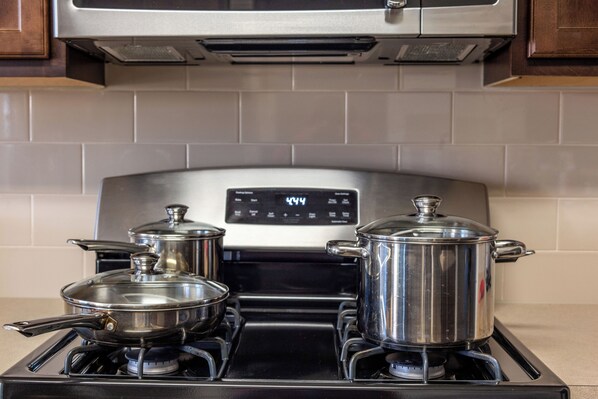 A kitchen with a stove, two pots, and a digital display. - Room C, >30 days, Near Medical Center, WOMEN ONLY (Houston)