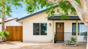 Una casa a un piano con recinzione in legno, una porta d'ingresso e un piccolo portico con una sedia.