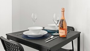 A table set with white bowls, blue plates, and a bottle of rosé wine.