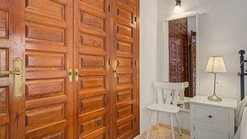 Une pièce comprenant une armoire en bois, une chaise blanche, une petite table et un miroir.