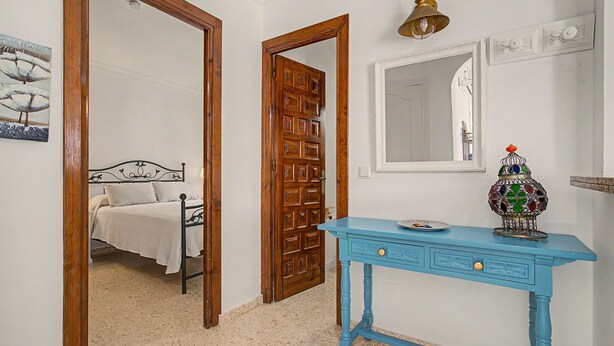 Une chambre à coucher avec un lit, une porte en bois, une commode bleue et un miroir.