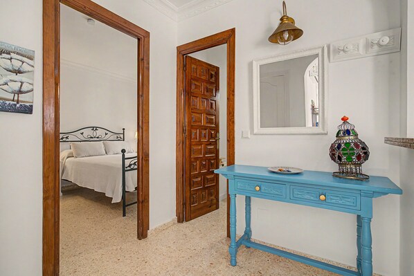 A bedroom with a bed, a wooden door, a blue dresser, and a mirror.