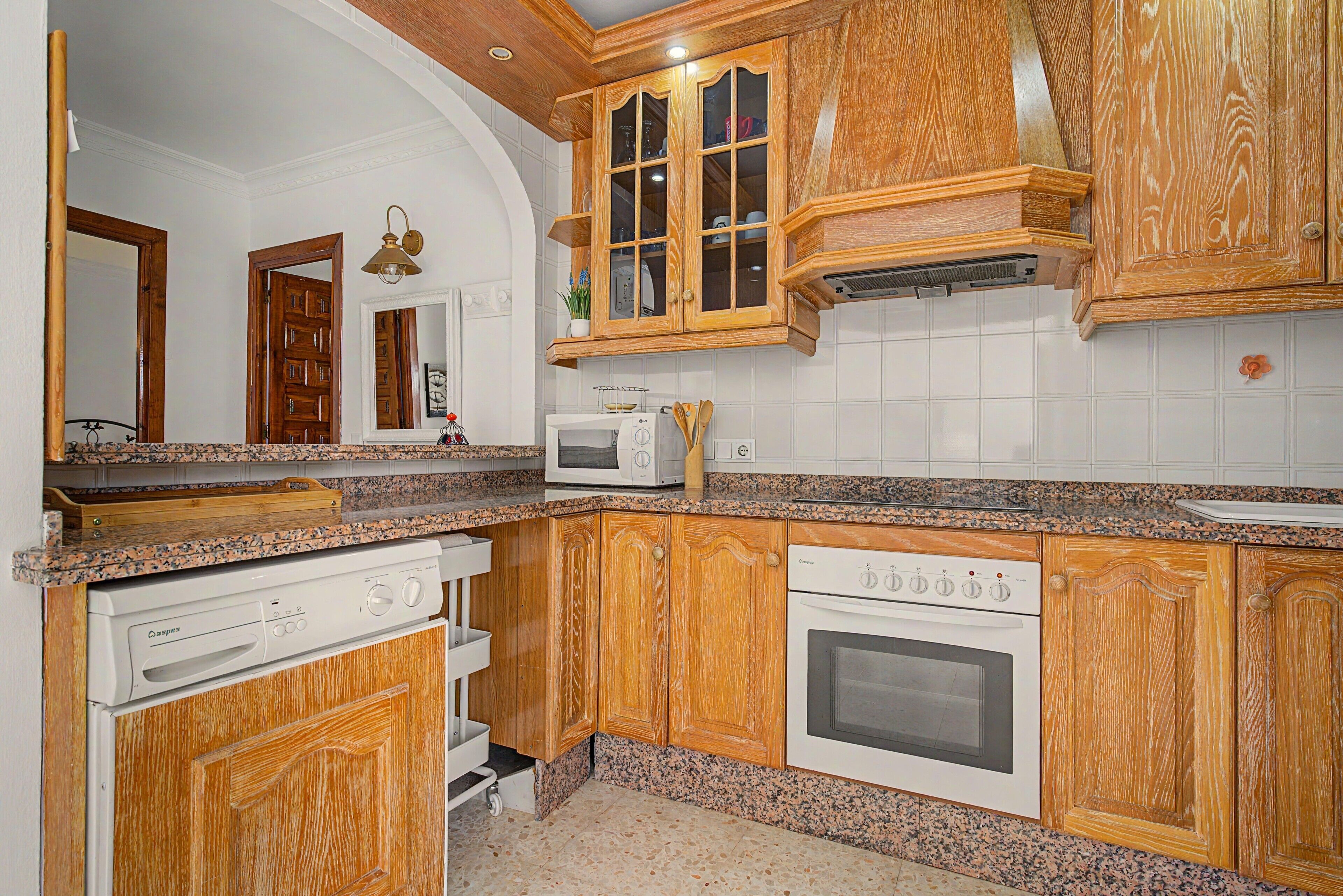 Eine Küche mit Holzausstattung, einer Mikrowelle, einem Backofen und einem Geschirrspüler.