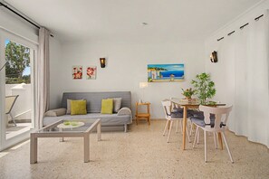 A modern living room with a sofa, coffee table, and dining area with chairs and a table.