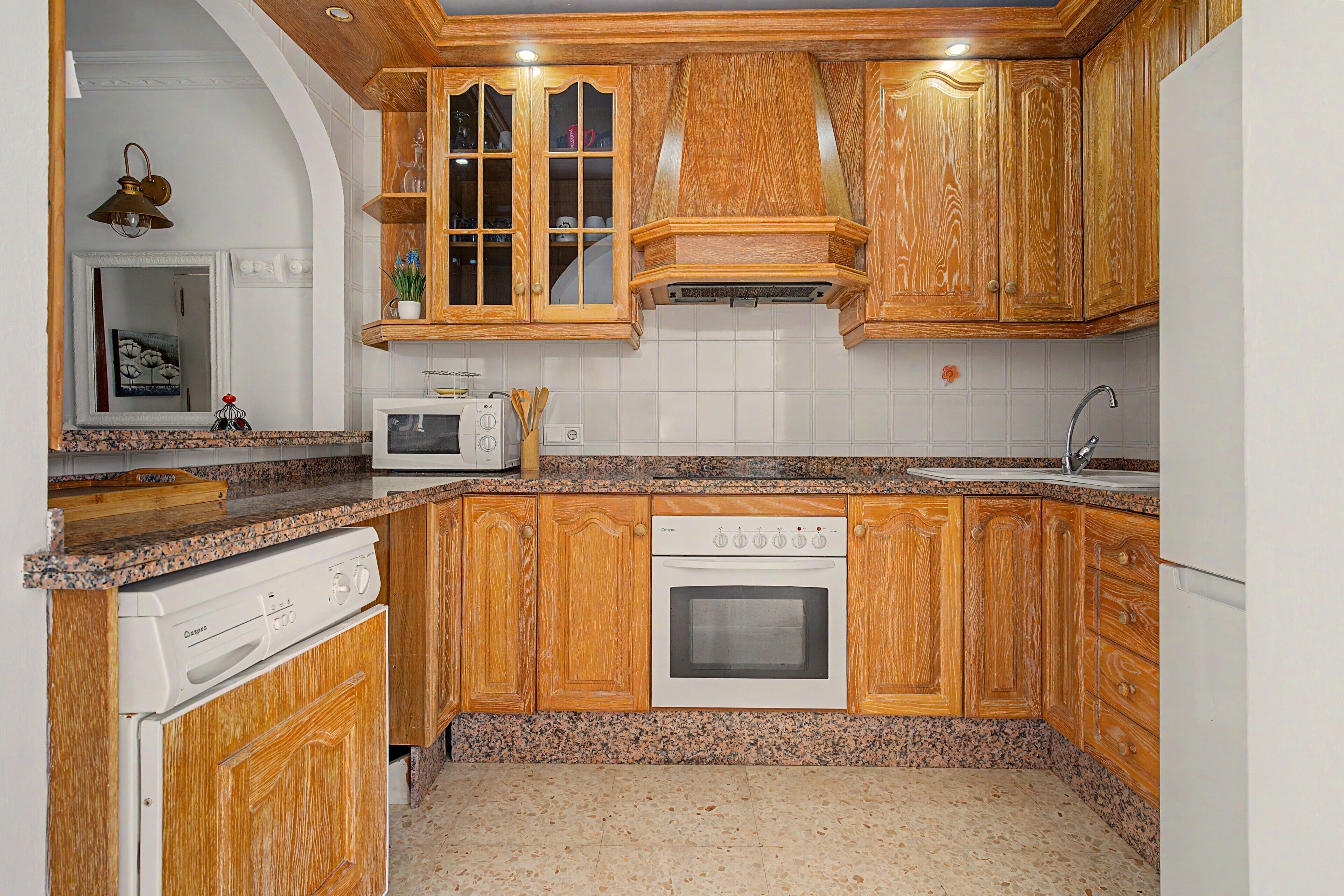 A kitchen with wooden cabinets, a microwave, a stove, and a sink.