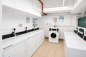Une laverie équipée de plusieurs machines à laver, d’un sèche-linge et de panneaux de commande.