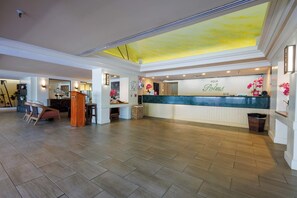 A hotel reception area with a counter, a reception desk, and a ceiling with a yellow design. - The Aqua Palms | Near Waikiki Beach + Free Parking (Honolulu)