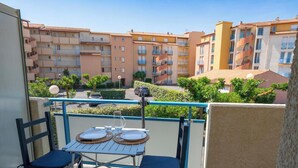 Un balcón con una mesa lista para dos personas, con vista a una zona residencial y edificios de varios pisos.