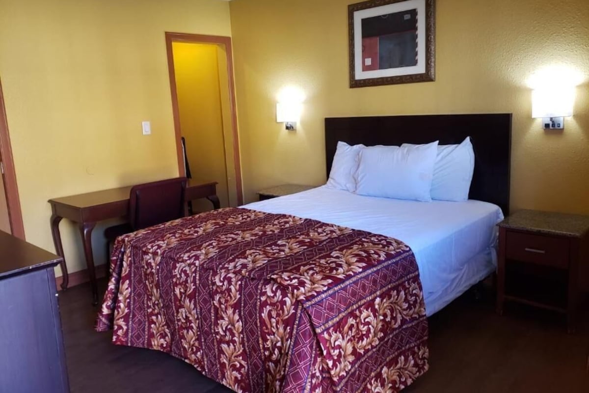 Una habitación de hotel con una cama, un escritorio y una silla.