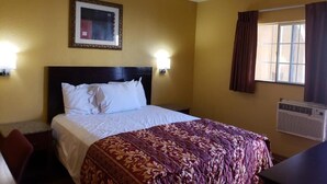 A hotel room with a bed, a desk, a chair, a framed picture on the wall, and a window with curtains. - Providencia Motel (Burbank)
