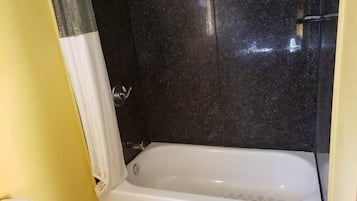 Un baño con bañera, inodoro y zona de ducha.