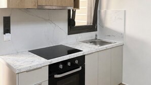 A modern kitchen with a black stove, white cabinets, and a wooden upper cabinet. -   Junior Suite with Modern Design in Chania (Chania)