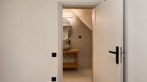 A hallway leading to a bathroom with a wooden vanity, a mirror, and a light fixture. -   Junior Suite with Modern Design in Chania (Chania)