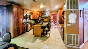 Una cocina con armarios de madera, una isla central y una zona de comedor con sillas.