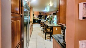 Una cocina con armarios de madera, un refrigerador, un comedor con sillas y una encimera.