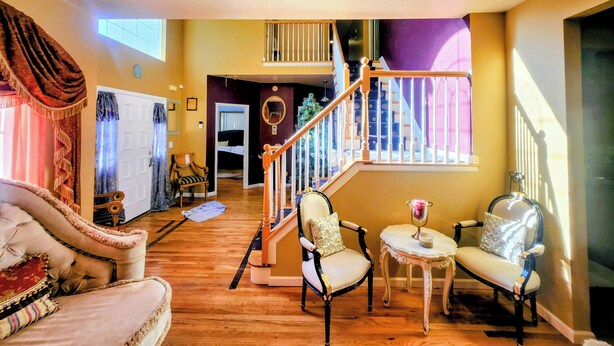 Amplia sala de estar con una escalera, un sofá, dos sillones y una mesita.
