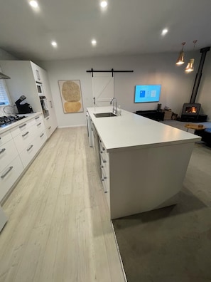 A modern kitchen with a central island, built-in appliances, and a large window.