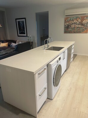 Een kleine keuken met een ingebouwde wasmachine en droger, een spoelbak en een aanrecht.