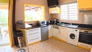 A compact kitchen with a microwave, coffee maker, sink, and washing machine. - Creole bungalow with views of the ocean and tropical scenery – Le Tapeur, Guadeloupe (Pointe-Noire)