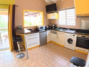 Cozinha compacta equipada com micro-ondas, cafeteira, pia e máquina de lavar roupa.