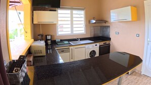A compact kitchen with a washing machine, a coffee maker, and a microwave. - Creole bungalow with views of the ocean and tropical scenery – Le Tapeur, Guadeloupe (Pointe-Noire)