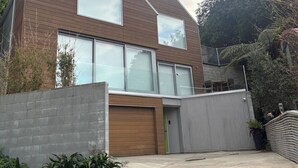 A modern two-story house with large windows, a garage, and a gated entrance. - Stunning beachside family retreat (Wellington)
