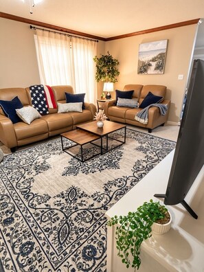 A living room with two sofas, a coffee table, a TV, and a patterned rug.