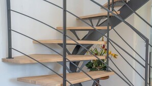 A modern staircase with wooden steps and metal railings. - Maison en pierre dans un hameau privé (Pont-l'Abbé)
