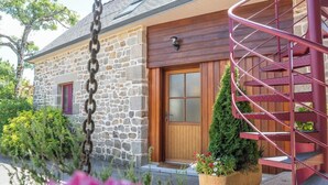 A stone building with a wooden door, a spiral staircase, and a potted plant in the foreground. - Maison en pierre dans un hameau privé (Pont-l'Abbé)