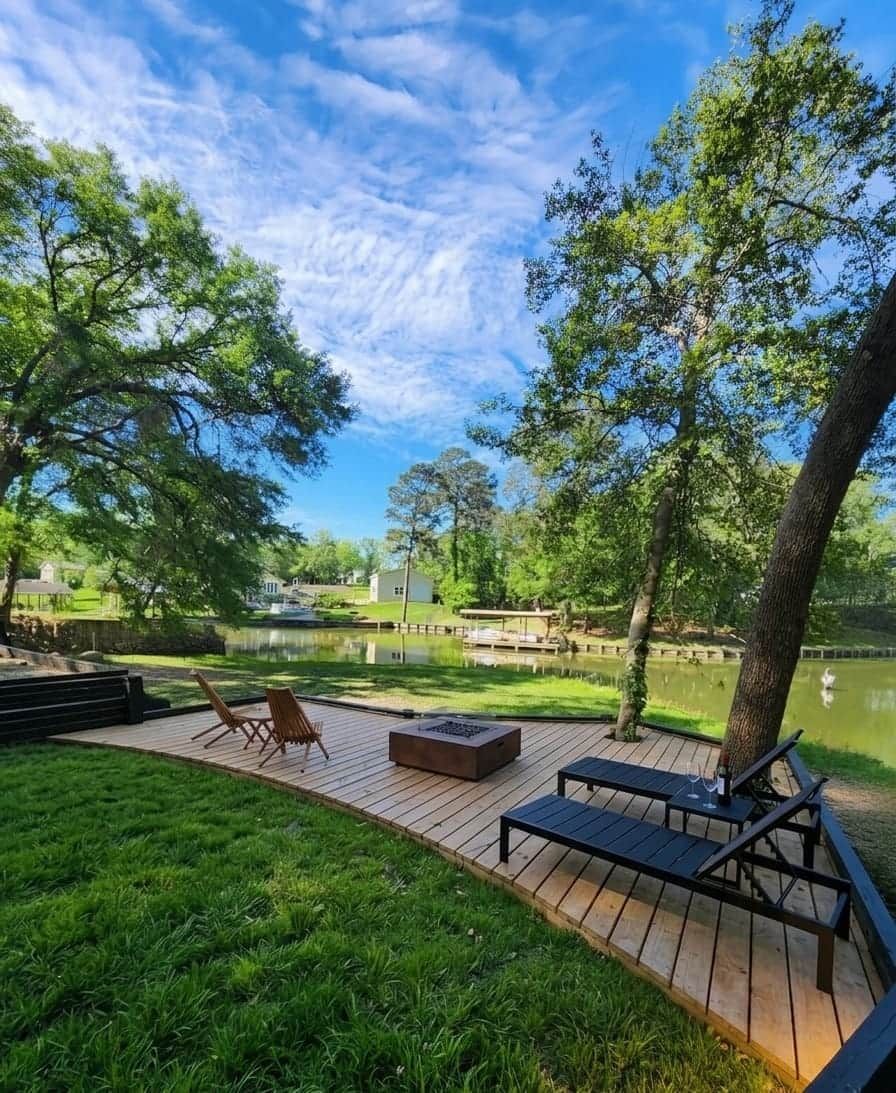 Een terras met buitenmeubilair met uitzicht op een waterpartij, omgeven door bomen.