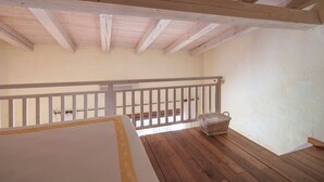 Habitació amb sostre de fusta, barana blanca i terra de fusta.