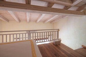 Ein Zimmer mit Holzbalkendecke, weißer Geländer und Holzboden.