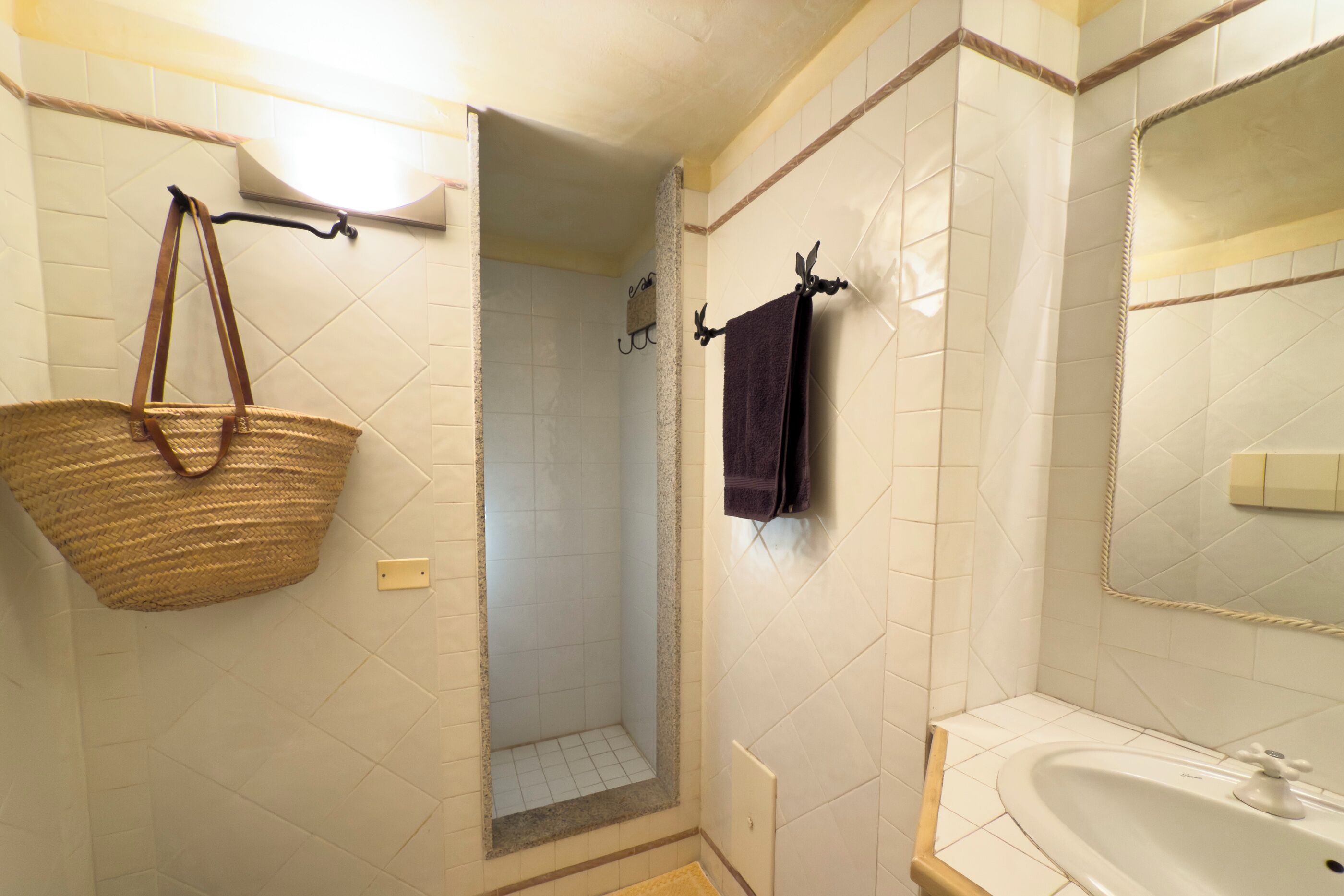 Ein Badezimmer mit Dusche, Waschbecken und einer hängenden Körbchen.