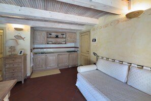 Habitación compacta con kitchenette, una cama y una mesita.