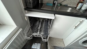 Una cocina con lavavajillas, fregadero y soporte para utensilios.