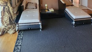 Een ruime woonkamer met een zithoek, een eettafel en een keuken op de achtergrond.