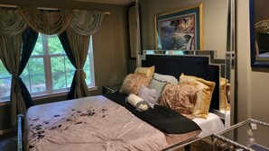 Een hotelkamer met een bed, nachtkastje, raam met gordijnen en een schilderij aan de muur.