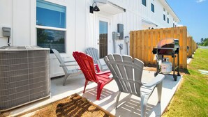 A white house with a patio area featuring outdoor seating, an air conditioning unit, and a barbecue grill. - Brand New 3-bedroom townhome with AC in the heart of Orange Beach (Orange Beach)
