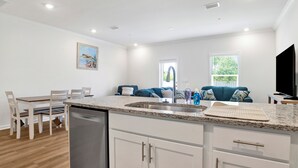 A modern kitchen with a dishwasher, white cabinets, and a granite countertop. - Brand New 3-bedroom townhome with AC in the heart of Orange Beach (Orange Beach)