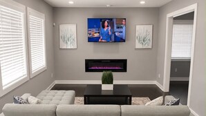 A modern living room with a large sectional sofa, a flat-screen TV, and artwork on the walls.