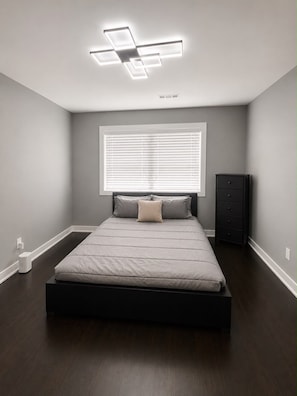 A bedroom with a bed, a window with blinds, a nightstand, and a ceiling light fixture. - Cozy Modern Escape Near Downtown ATL (Atlanta)