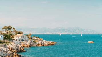 A coastal town with rocky shores, white buildings, and sailboats on the sea.