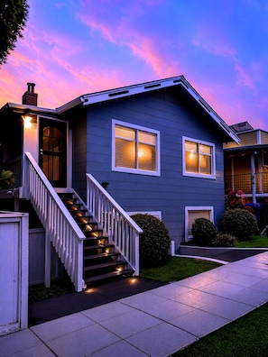 A two-story house with a front staircase, a garage, and a well-maintained lawn. - CasaViva Vista · Top-Floor 2BR with Private Porch, City Views, Walk to Eats (San Diego)