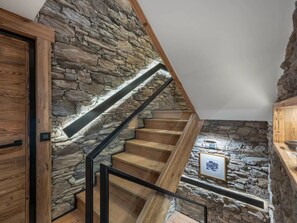 A staircase with wooden steps and stone walls, a wooden door, and a framed picture on the wall. - Chalet Bacaro - 12 guests (Les Allues)