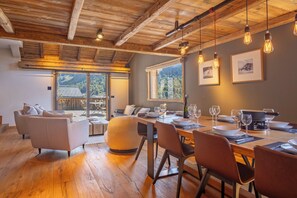 Un coin repas avec une table en bois dressée pour le repas, un canapé et une vue sur l’extérieur.